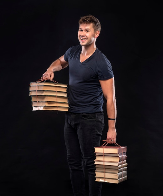 Homme souriant avec pile de livres sur fond noir