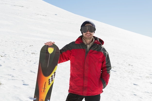 Homme souriant avec planche de ski debout sur la neige