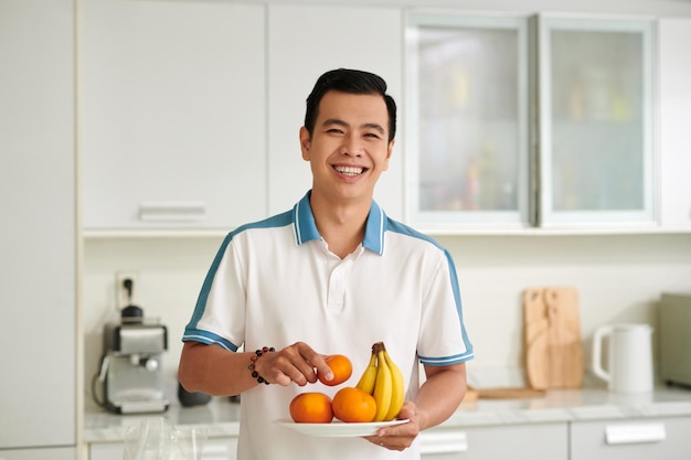 Un homme souriant avec un plat de fruits frais