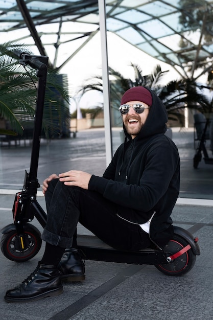 Homme souriant plein coup sur scooter électrique