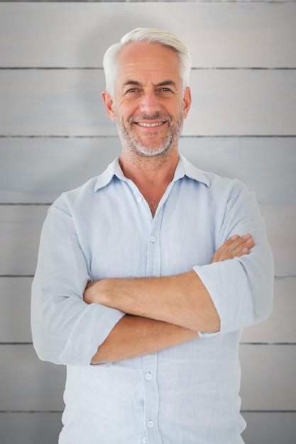 Photo homme souriant posant avec les bras croisés contre des planches de bois