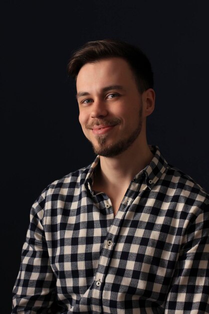 Un homme souriant pose sur un mur avec des ombres