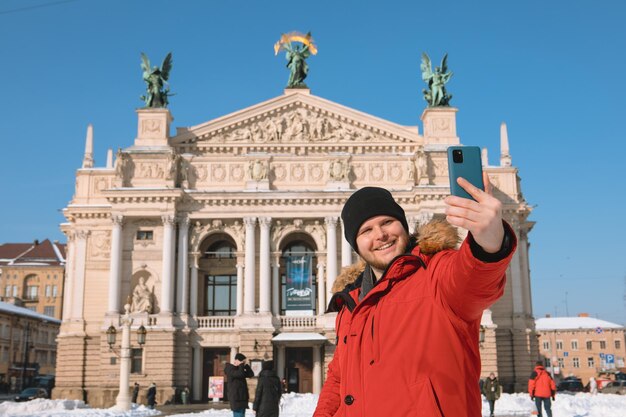 Homme souriant prenant selfie devant le bâtiment de l'opéra