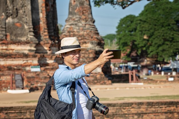 Photo un homme souriant prend un selfie en se tenant contre le temple.