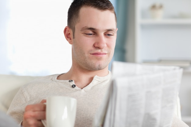 Homme souriant, prendre un café en lisant les nouvelles