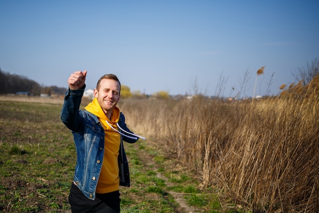 Homme souriant profitant du vent qui souffle dans la forêt. Heureux homme ressentant de la joie en marchant dans la nature, espace libre sur fond d'arbres verts. Amour de la vie, joie, air frais, concept de rénovation