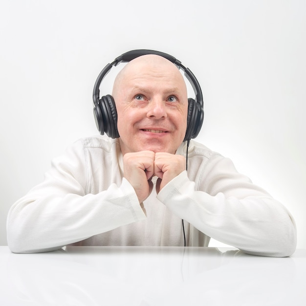 Homme souriant en pull blanc, écouter de la musique sur des écouteurs portables