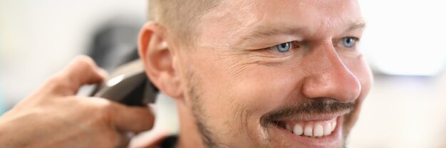 Homme souriant qui a une coupe de cheveux au salon de coiffure.