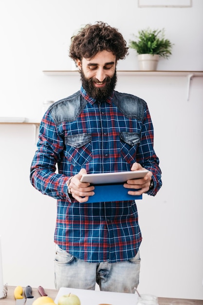 Homme souriant à la recherche de recettes de smoothie avec tablette