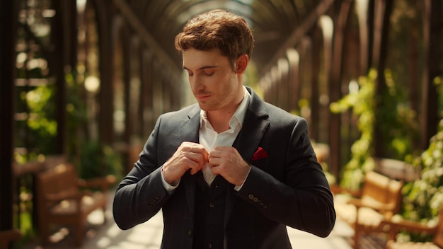 Homme souriant regardant la caméra dans le parc Groom se préparant à la cérémonie de mariage