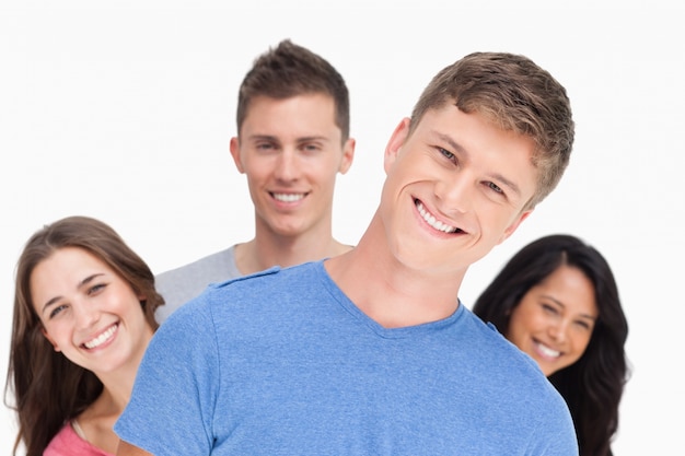 Un homme souriant avec sa tête inclinée et ses amis derrière lui