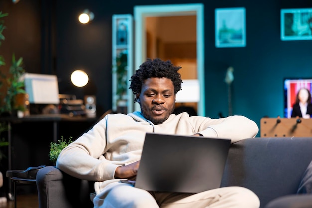 Un homme souriant se détend dans le salon en regardant des clips Internet drôles sur son ordinateur portable