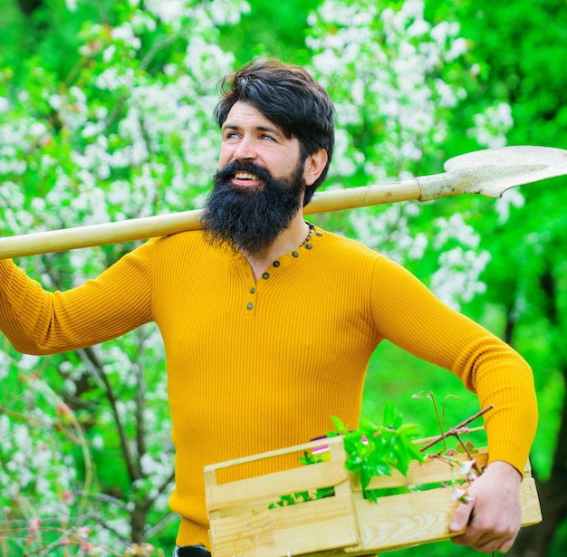 Homme souriant se préparant à planter un jardinier avec une bêche de jardinage ou une pelle de printemps dans le jardin