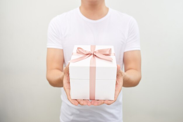 Homme souriant en t-shirt tenant une boîte-cadeau sur fond blanc