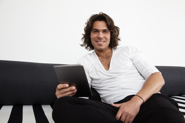 Homme souriant avec une tablette sur un canapé