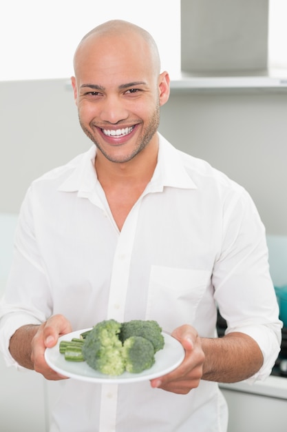 Homme souriant tenant une assiette de brocoli