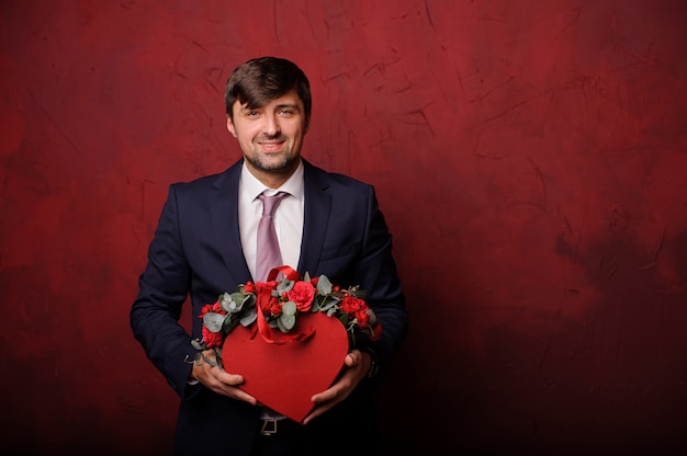 Homme souriant tenant une boîte rouge de fleurs