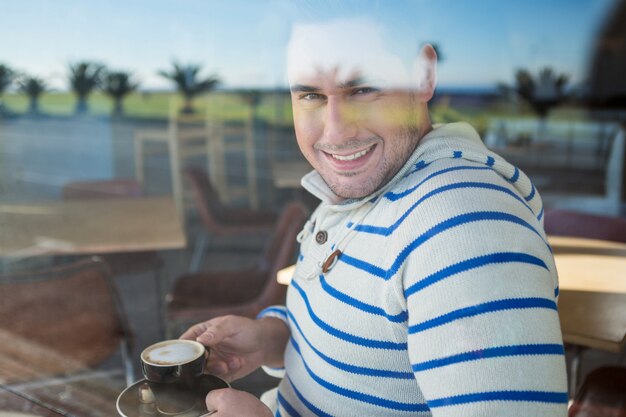 Homme souriant tenant une tasse de café