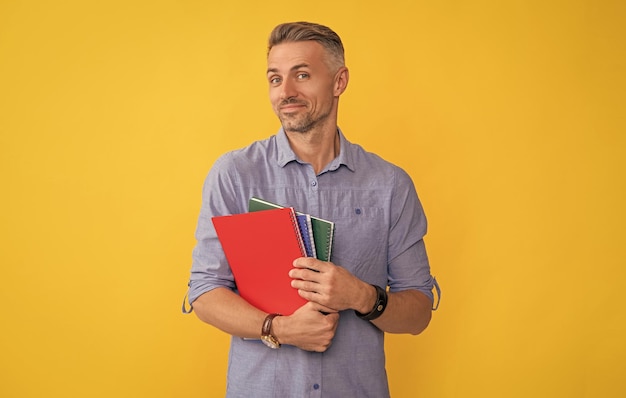 Un homme souriant tient un cahier d'école ou un professeur de planificateur