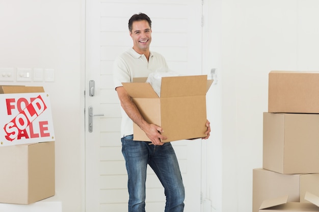 Homme souriant, transportant des boîtes dans une nouvelle maison