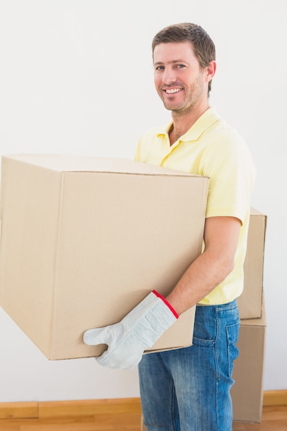 Homme souriant transportant des cartons de déménagement à la maison