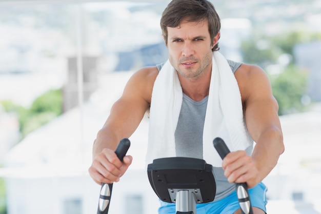 Homme souriant, travaillant à la classe de spinning dans la salle de gym lumineuse