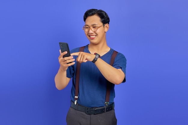 Homme souriant utilisant un téléphone portable pour parcourir avec un espace vide sur fond violet