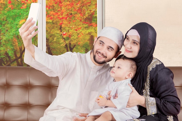 Photo un homme souriant utilisant un téléphone portable avec sa famille sur le canapé