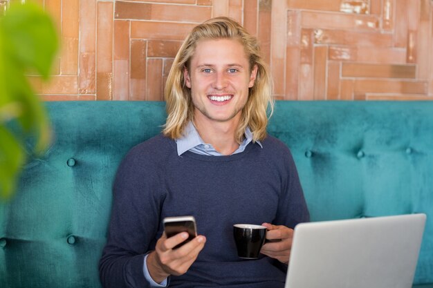 Homme souriant, utilisation, téléphone portable, quoique, avoir, tasse café