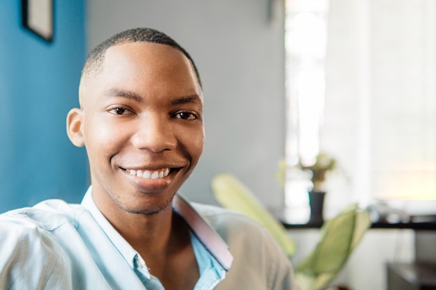 Homme avec un sourire blanc parfait regardant la caméra à la maison