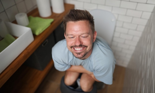 Photo un homme avec un sourire satisfait est assis sur les toilettes.