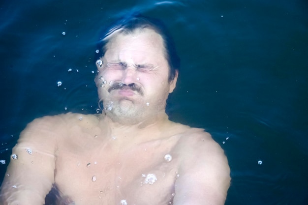 Homme sous l'eau avec les yeux fermés