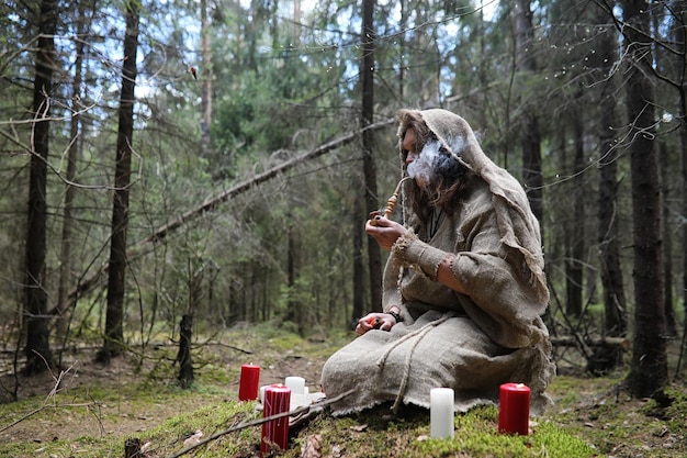 Un homme en soutane passe un rituel dans une sombre forêt