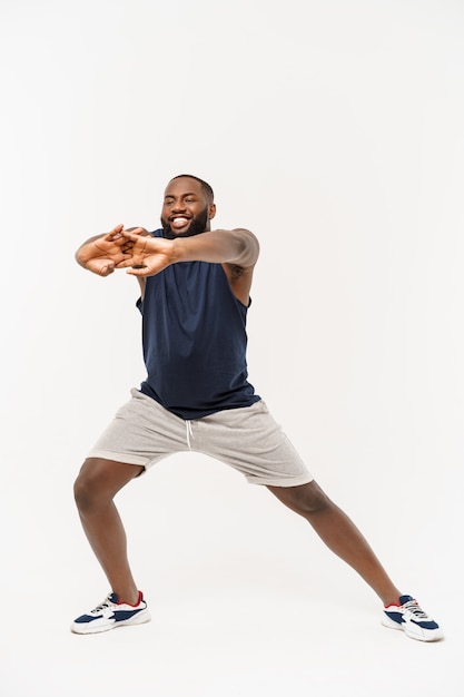 Homme de sport africain exerçant et s'étendant sur blanc