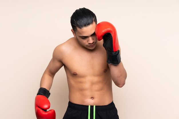 Homme de sport asiatique isolé sur fond beige avec des gants de boxe