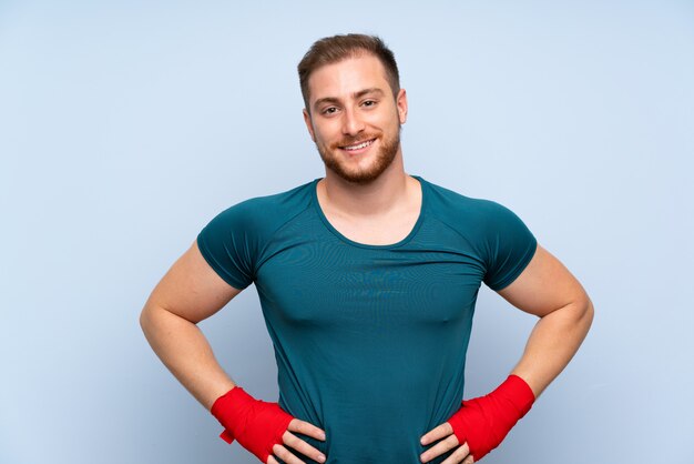 Homme de sport blonde sur un mur bleu dans des bandages de boxe