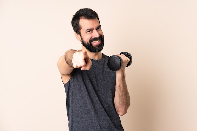 Homme de sport caucasien avec barbe faisant de l'haltérophilie sur fond isolé pointant vers l'avant avec une expression heureuse