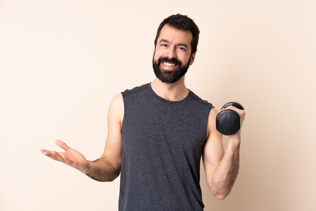 Homme de sport caucasien avec barbe faisant haltérophilie sur mur heureux et souriant