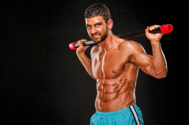 Homme de sport debout montrant la musculation musculaire sur fond noir concept de sport concept de remise en forme
