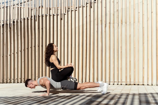 Homme de sport exerçant des planches avec une femme sur le dos dans la rue