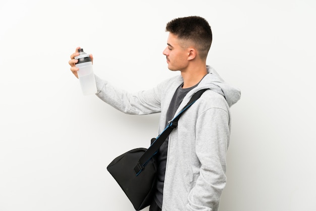 Homme de sport sur un mur blanc isolé avec une bouteille d'eau