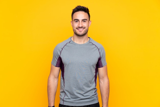 Homme de sport sur mur jaune isolé heureux et souriant