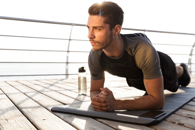 L'homme de sport en plein air sur la plage fait des exercices de sport