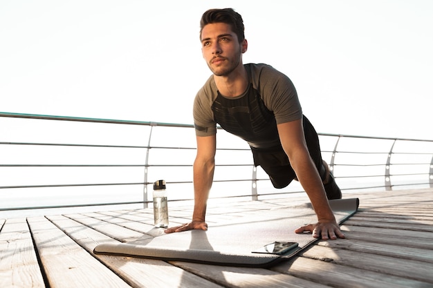 Photo l'homme de sport en plein air sur la plage fait des exercices de sport