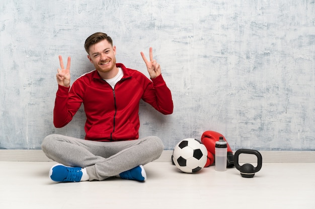 Homme de sport rousse montrant le signe de la victoire à deux mains