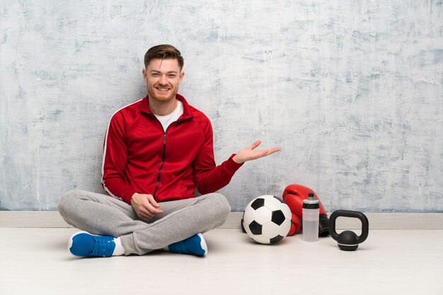 Homme de sport rousse présentant une idée tout en regardant en souriant