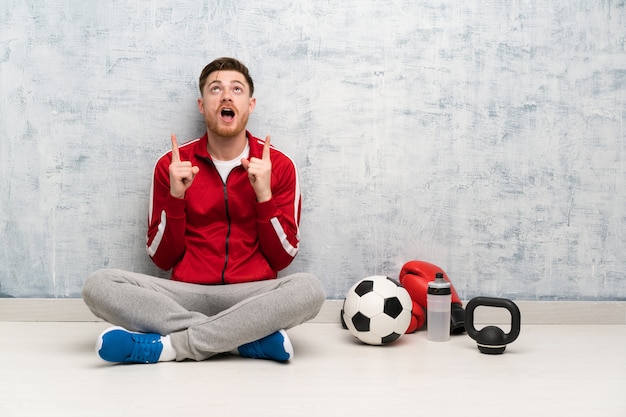 Homme de sport rousse surpris et pointant vers le haut