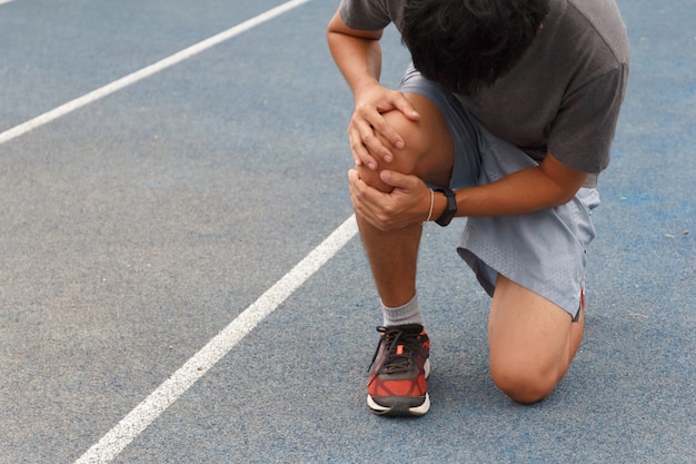 Homme de sport souffrant de douleur sur le sport en cours d'exécution blessure au genou après avoir couru. Blessure du concept d'entraînement.