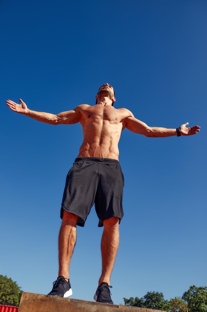 Homme sportif en bonne forme physique faisant des exercices intensifs sur une boîte en bois tout en faisant de l'entraînement de gym en plein air