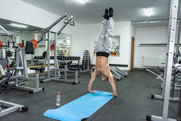 Homme sportif dans une salle de sport debout sur les mains